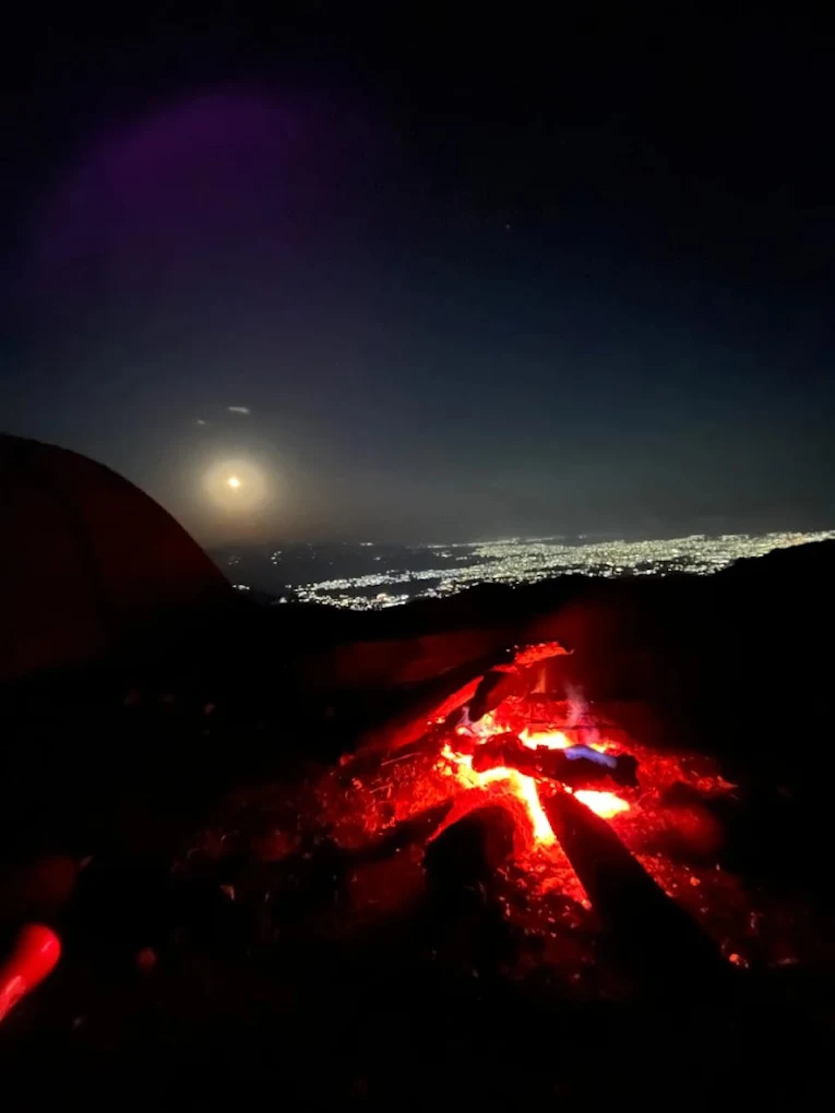 Bonfire embers with city and moon