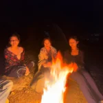 Campers around the shared bonfire at night at Camp George Everest