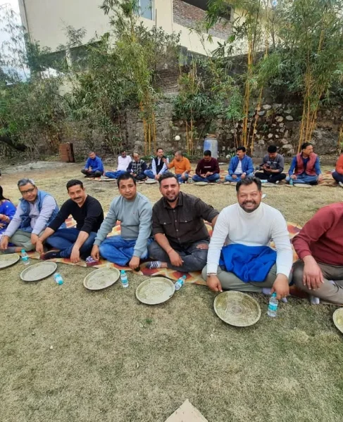 Villagers sharing a traditional pahadi community feast seated on the ground