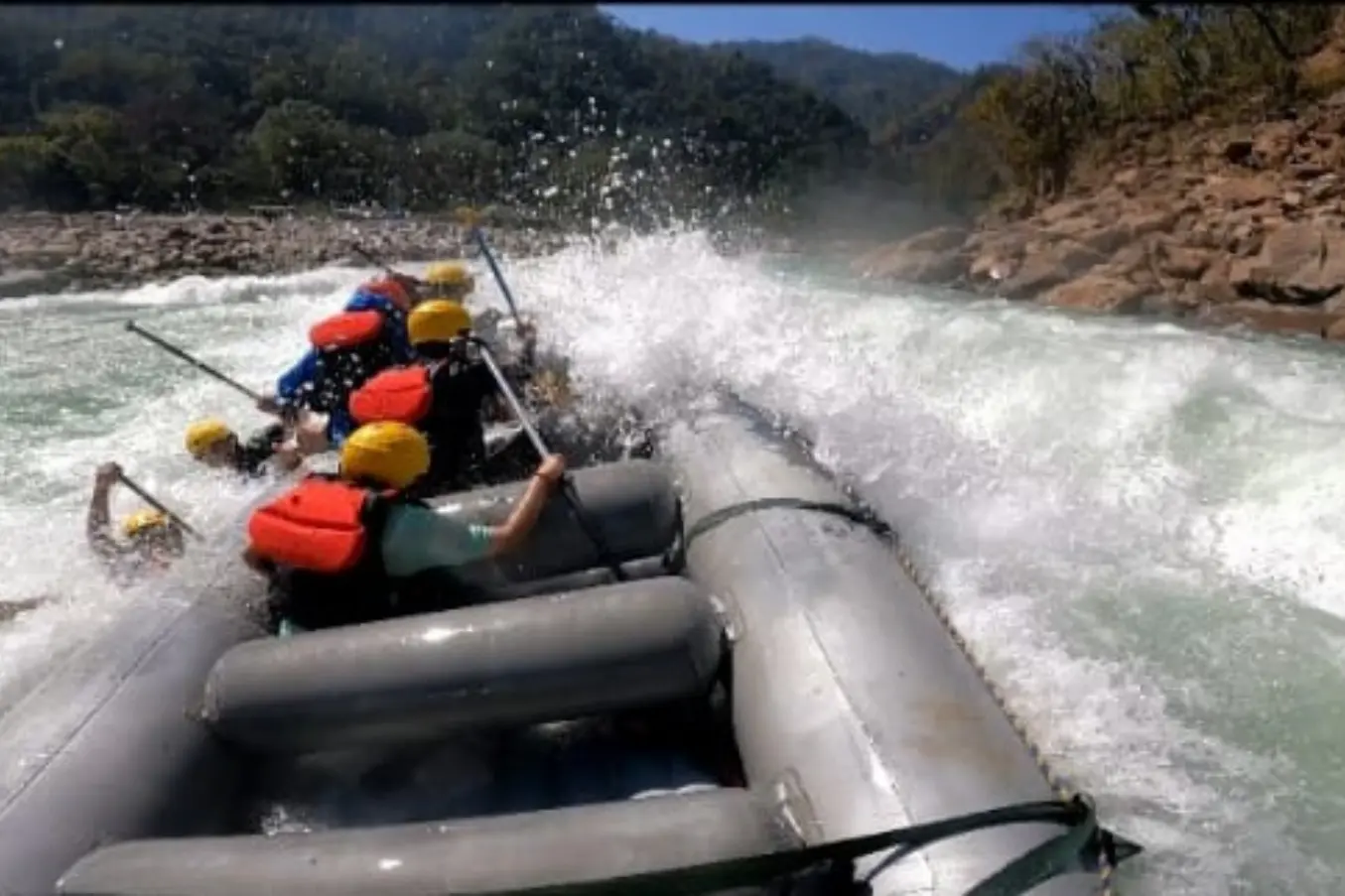 Rafting team paddling through a Marine Drive rapid on the Ganga during a 26 km whitewater rafting trip in Rishikesh