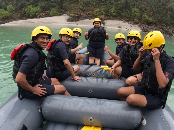 Smiling group on a grey raft mid-river during a 16 km Shivpuri rafting trip in Rishikesh