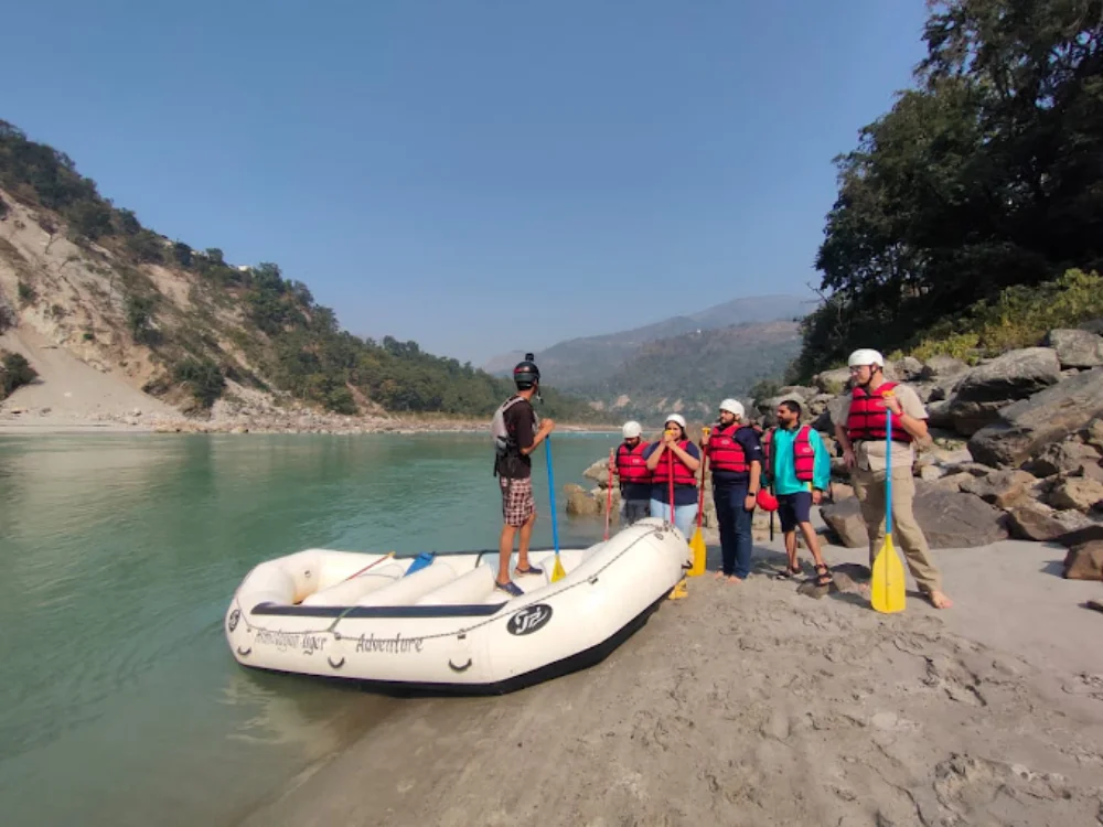 Pahadi House rafting group with paddles and helmets at the NIM Beach put-in for river rafting in Rishikesh on the Ganga