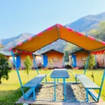Tent cottages and picnic gazebo with mountain backdrop at Himalayan Ganga Retreat, Rattapani