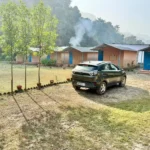 Cottages and garden lawn with morning mist at Himalayan Ganga Retreat
