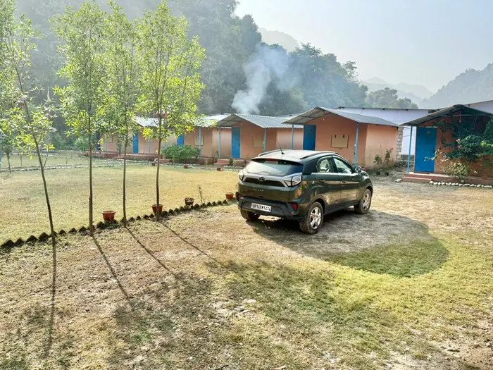 Cottages and garden lawn with morning mist at Himalayan Ganga Retreat, riverside camp in Rishikesh