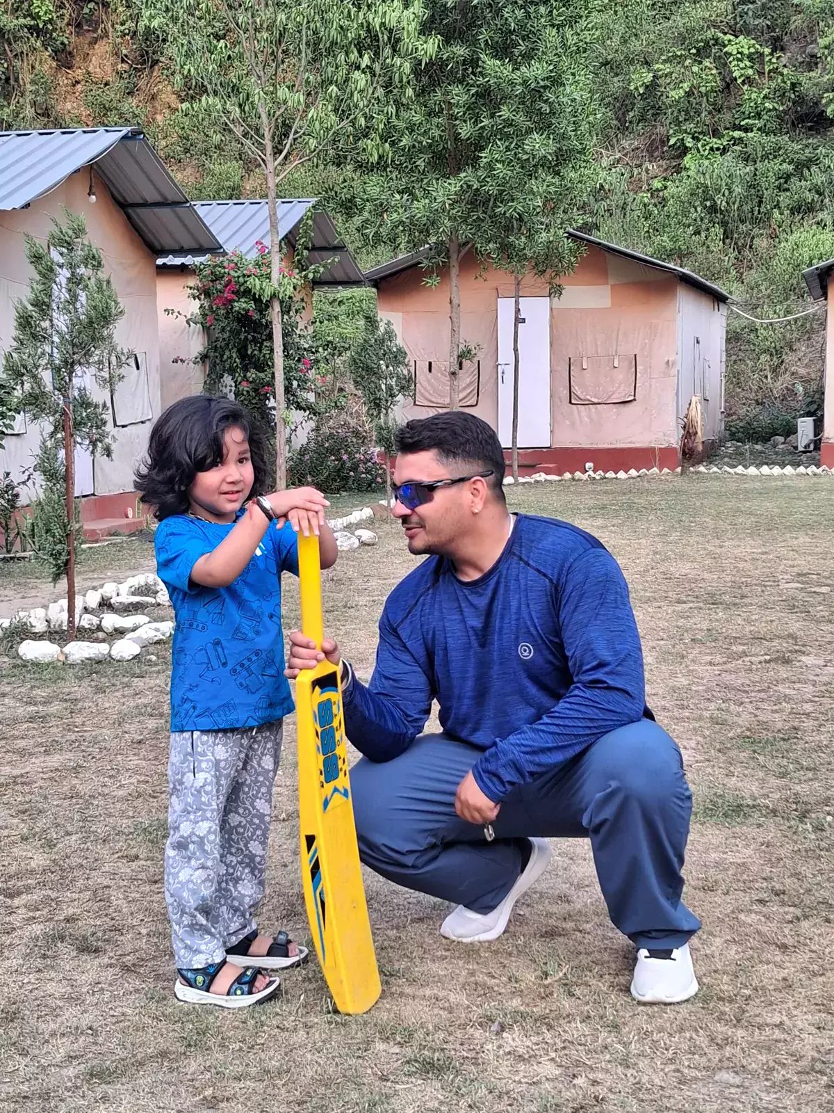 Father and child playing cricket on the lawn at Himalayan Ganga Retreat riverside camp, Rishikesh