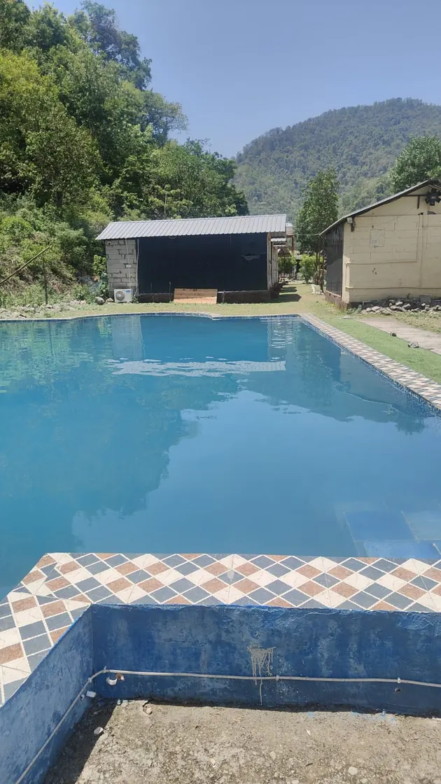 Swimming pool with mountain backdrop at Himalayan Ganga Retreat, riverside camp in Rishikesh
