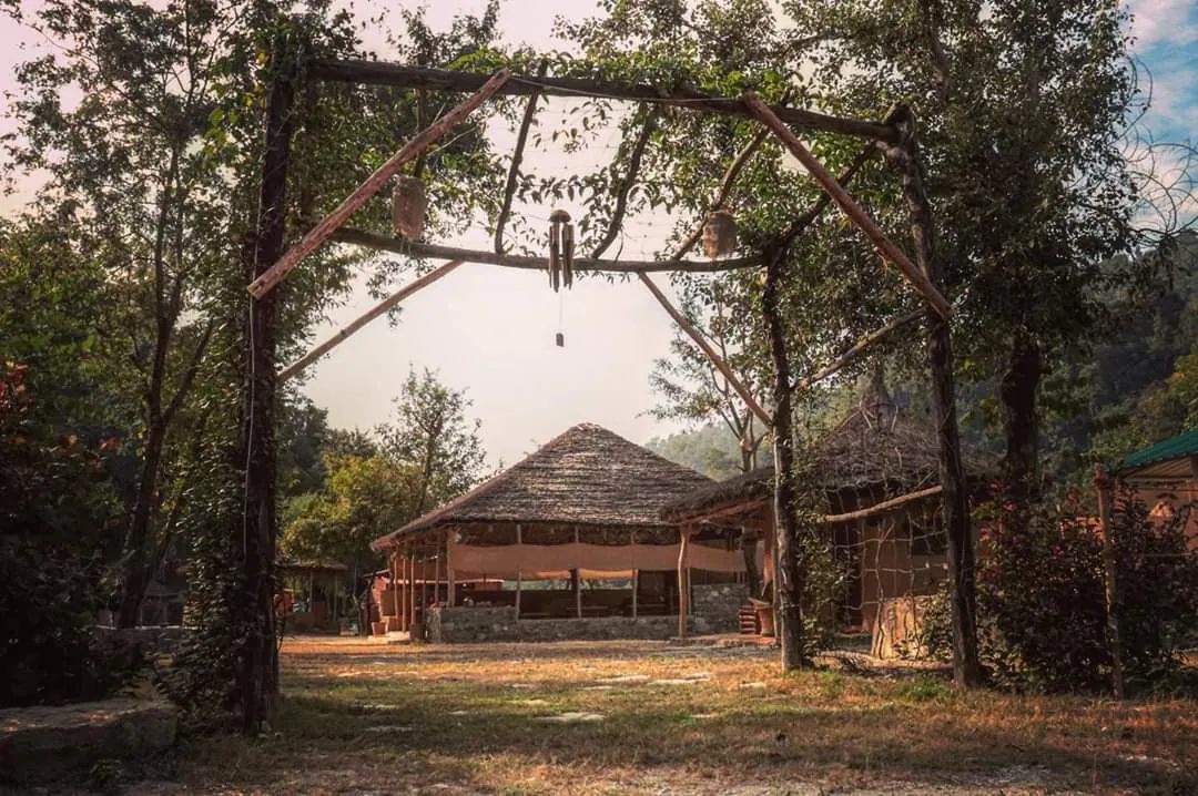 A thatched lounge and mud huts at a Pahadi House forest camp in Uttarakhand