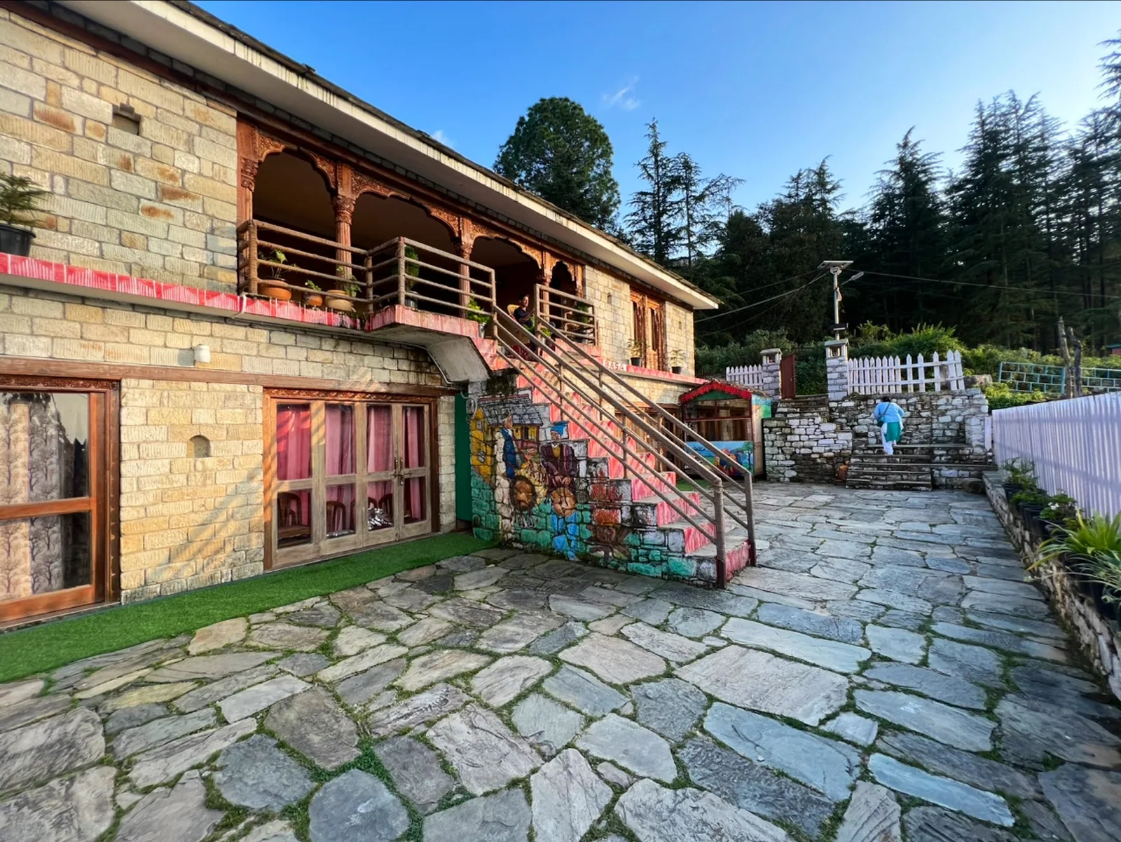 The stone facade and wooden upper floor of Basa Stay, Khirsu, seen from the courtyard