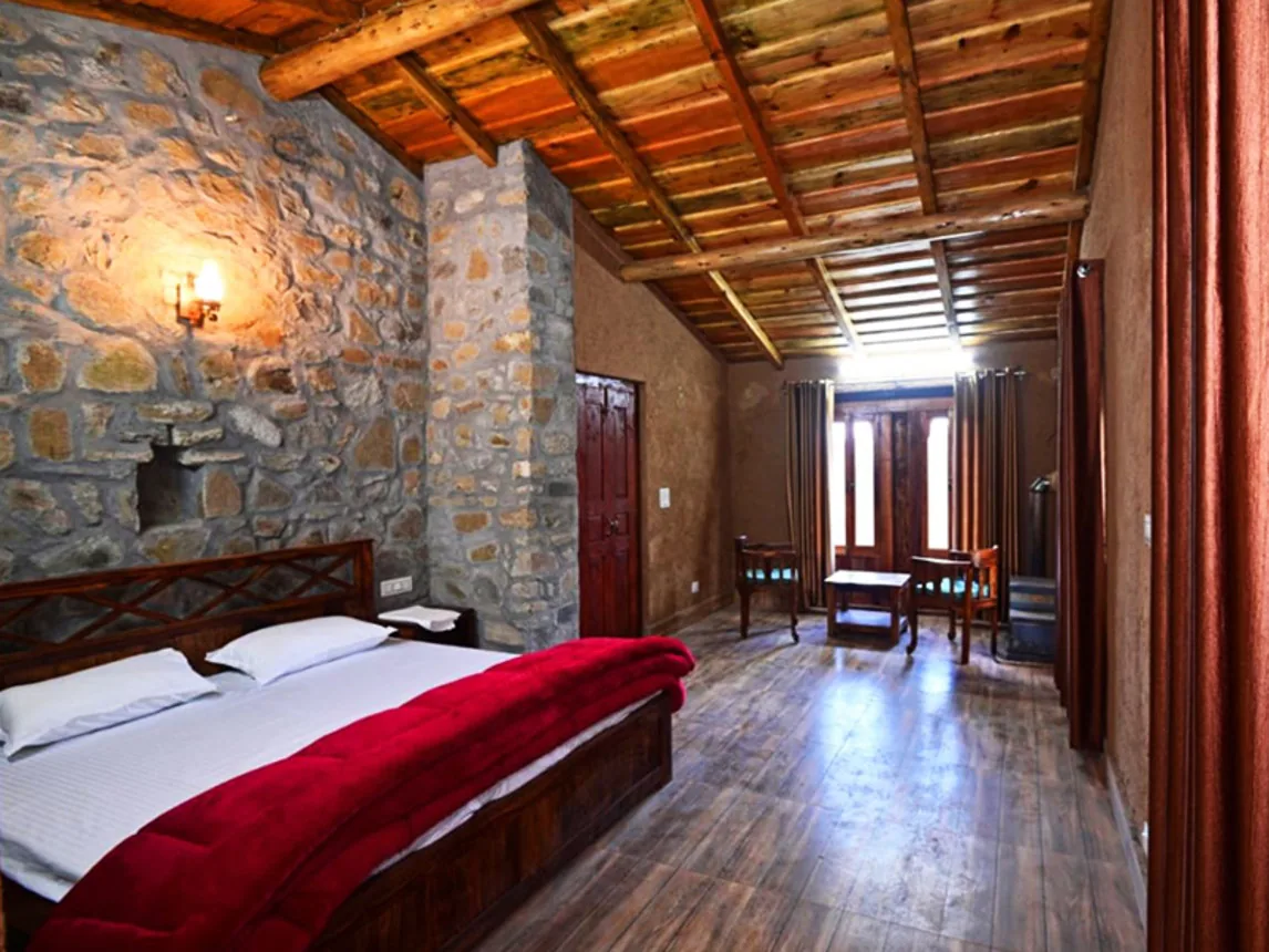 Wood panelled bedroom with a red bedspread at Basa Stay, Khirsu