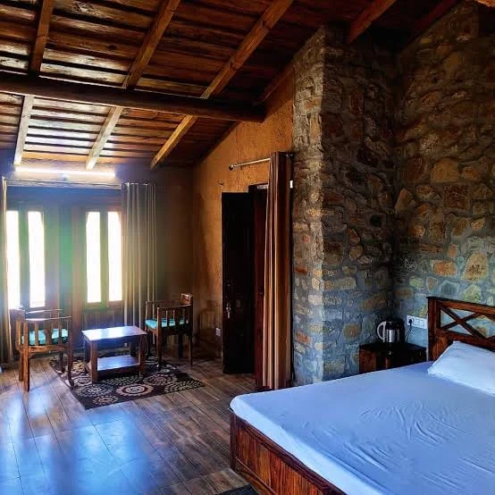 Room at Basa Stay with exposed stone walls, a timber ceiling and a wooden floor, Khirsu