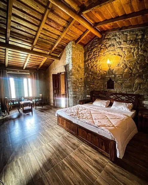 Bedroom at Basa Stay with a stone wall, lit alcove and wooden ceiling, Khirsu