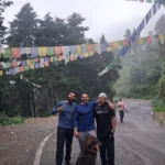 Guests and a dog on the forest road to George Everest Peak, under strings of prayer flags