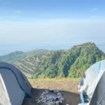 The view between two tents at Camp George Everest, across the forested Hathipaon ridge