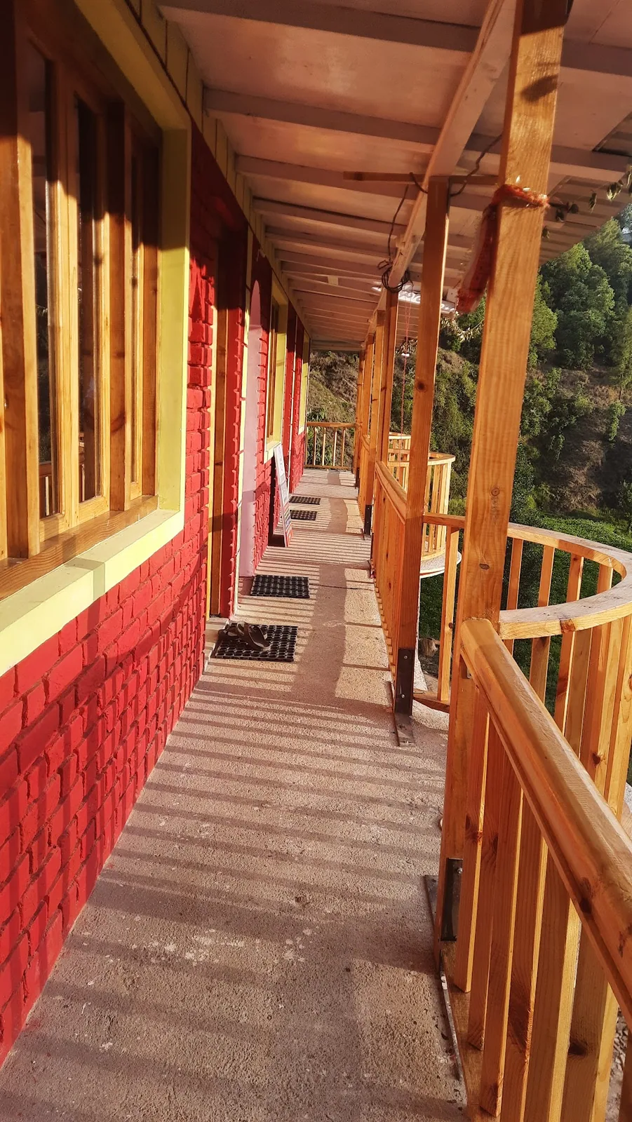 Wooden verandah running along the rooms at Ghughuti Homestay, Sunkiya