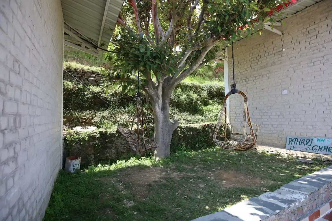 Garden with a hanging swing beside the Pahadi Ghar sign