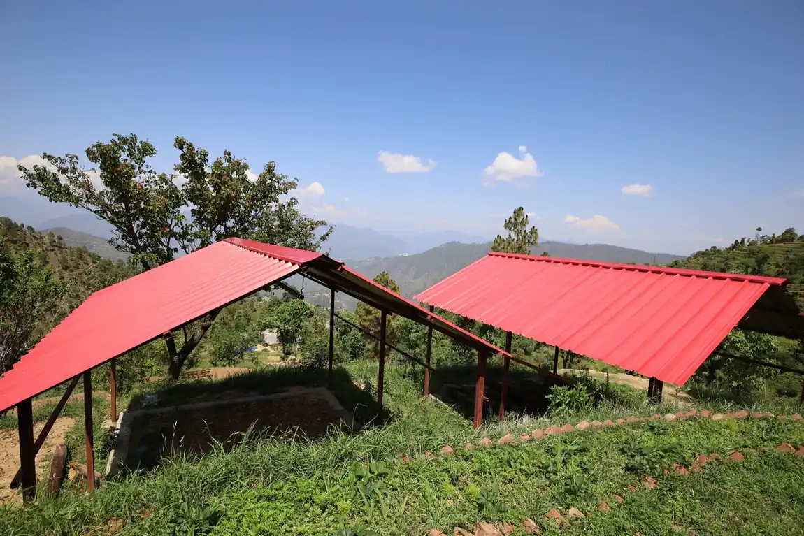 Red-roofed open shelters in the garden at Kanatal