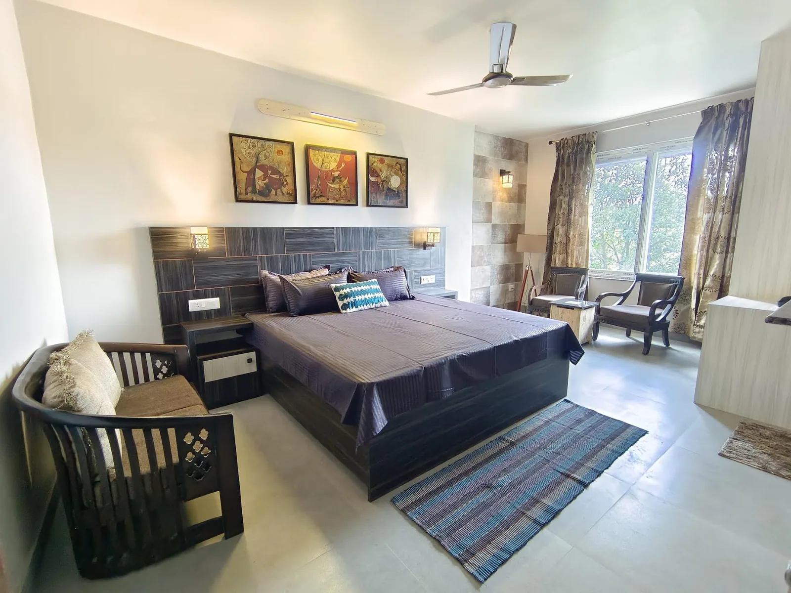 Bedroom with full height windows looking into the orchard at WindyRidge, Mukteshwar
